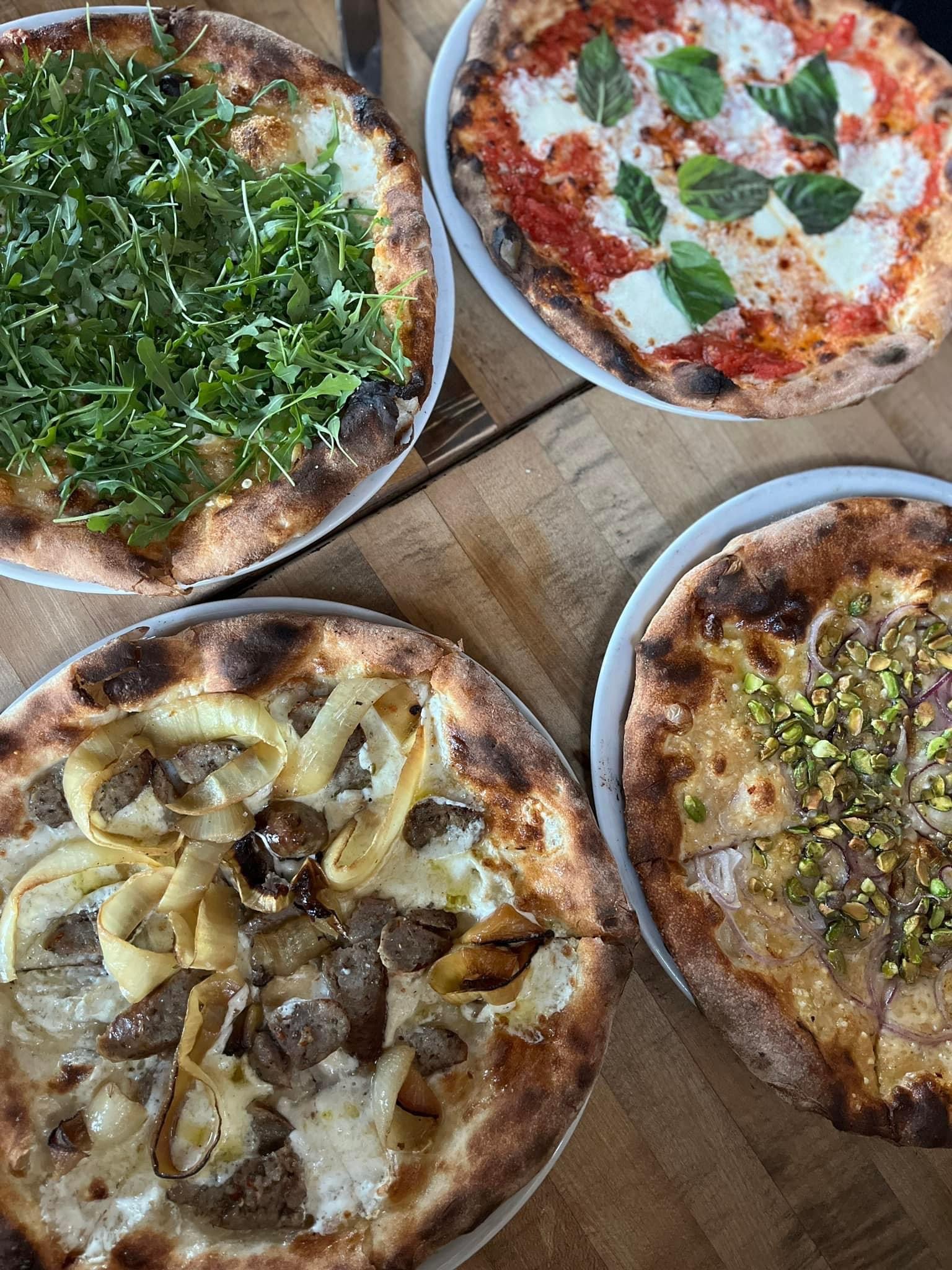 This photo displays four personal pizzas, all with various toppings.